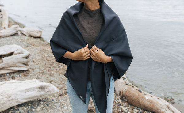 A Large Shepherd's Wool Utility Cloth in Matter Grey being worn as a shawl by a person at the beach.